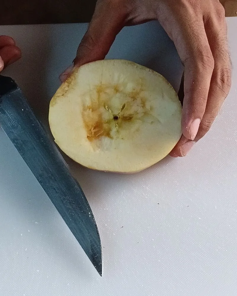 Slicing a fresh whole apple horizontally on a white cutting board to make healthy apple rings