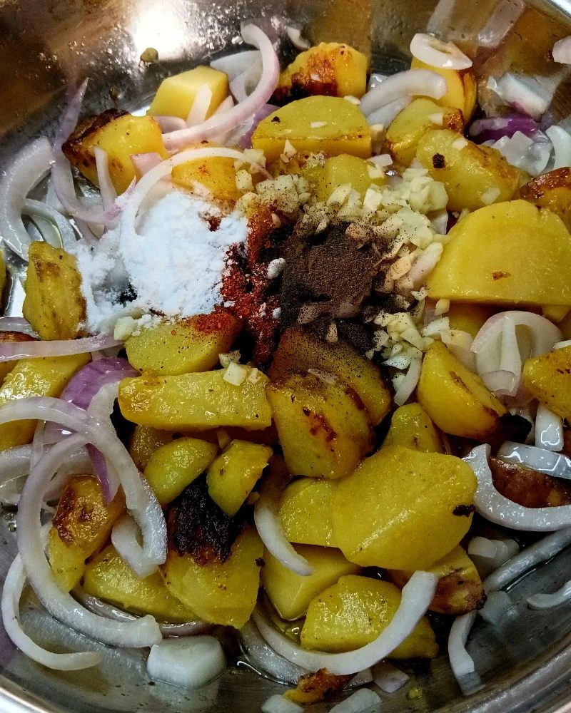 In a large bowl, toss the potatoes and sliced onion with oil, salt, pepper, and paprika until evenly coated.