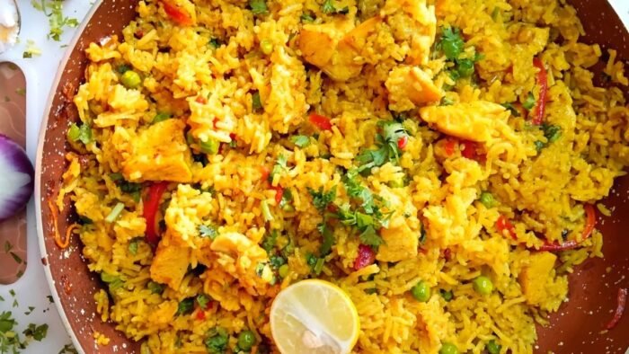 Overhead photo of healthy chicken yellow rice with turmeric, peas, and fresh cilantro in a ceramic bowl