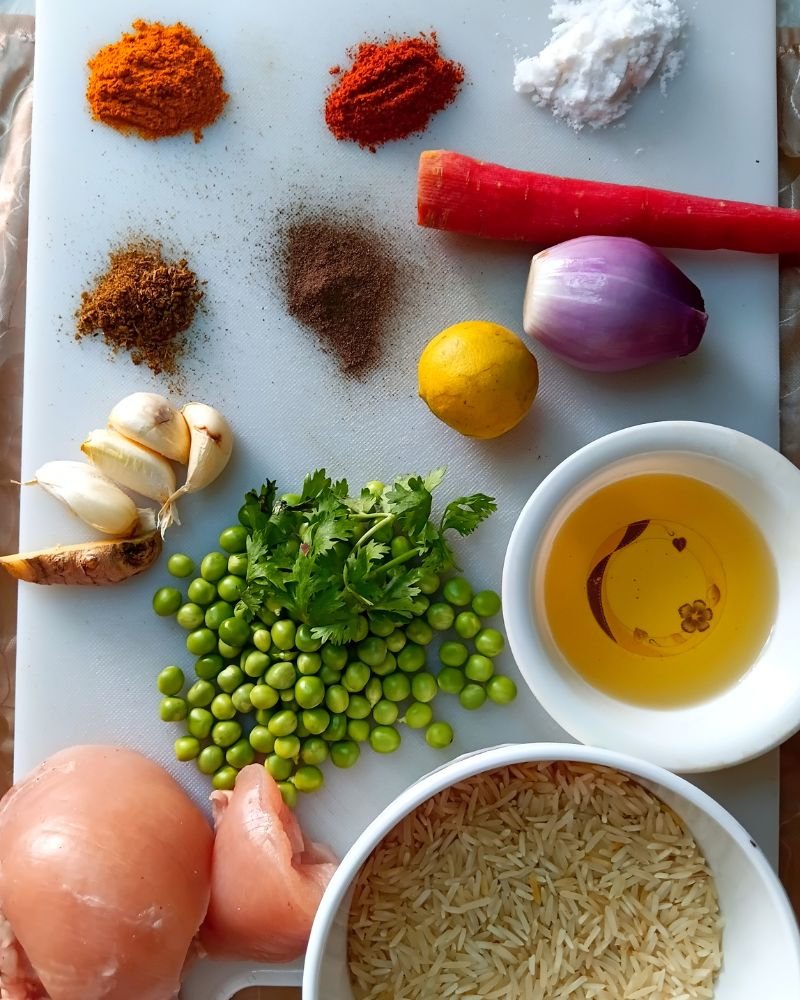 Raw ingredients for chicken yellow rice recipe including basmati rice, turmeric, chicken thighs, and vegetables